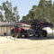 Two Vehicles, A Red Tractor And A Black Truck, Parked Under A Metal Carport With Trees In The Background - Saksby Wholesale
