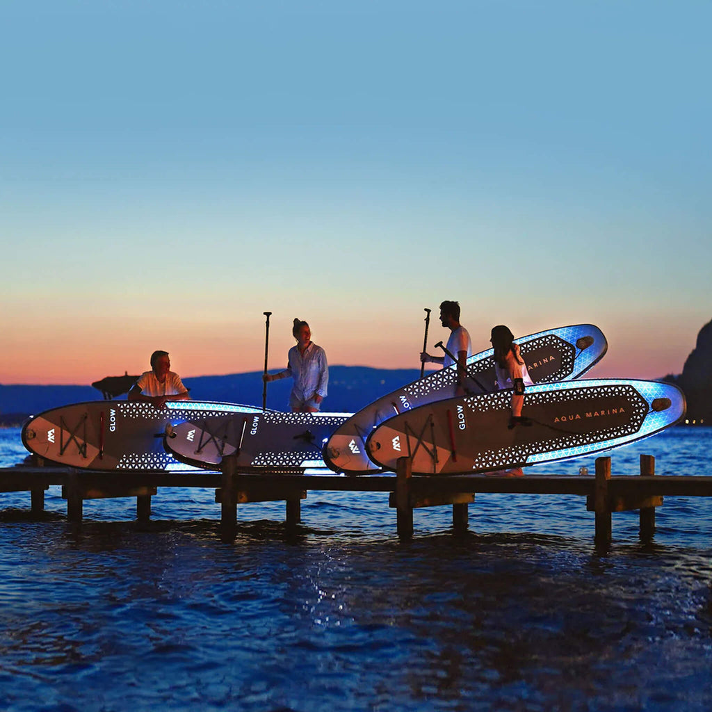 Aqua Marina Glow 10FT All-Around ISUP With Ambient Light System And Safety Leash [BT-24GL] (SAK48269) - Saksby Wholesale - Lifestyle With Four People On Shore Night View