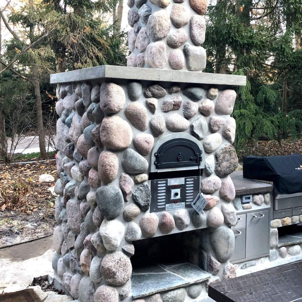 Chicago Brick Oven CBO-750 Commercial Hybrid Wood & Gas Fired Oven DIY Kit [CBO-O-KIT-750-HYB] (SAK75154) - Saksby Wholesale - Lifestyle Image Outside With Boulder Retaining Build