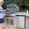 Kokomo Grills Maui BBQ Island With 33 Inch Round Bar LED Lights And Built In BBQ SAK25961 - Lifestyle With Man Cooking On Grill