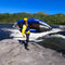 Person With A Kayak On Their Back Standing On A Rocky Shore With Mountains In The Background - Saksby Wholesale
