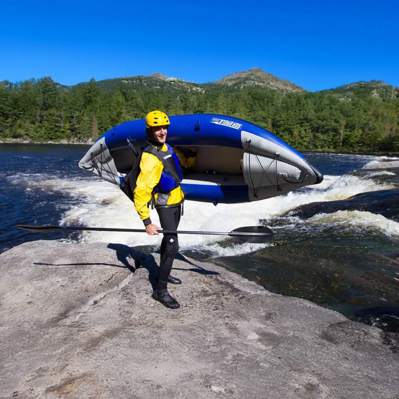 Person With A Kayak On Their Back Standing On A Rocky Shore With Mountains In The Background - Saksby Wholesale