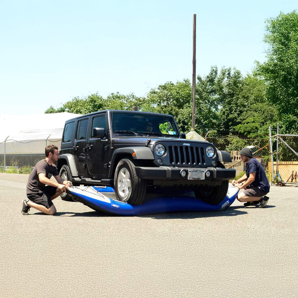 Two People Working On A Blue Object In Front Of A Black Jeep Wrangler - Saksby Wholesale