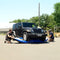 Two People Working On A Blue Object In Front Of A Black Jeep Wrangler - Saksby Wholesale