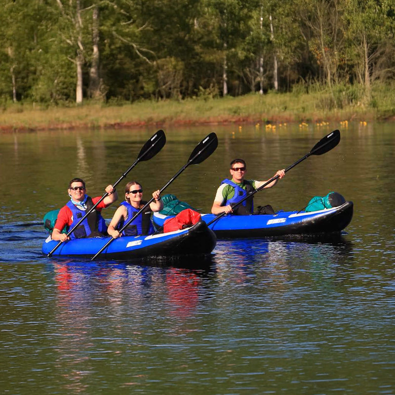 Three People Paddling A Blue Kayak On A Calm Lake With Trees In The Background - Saksby Wholesale