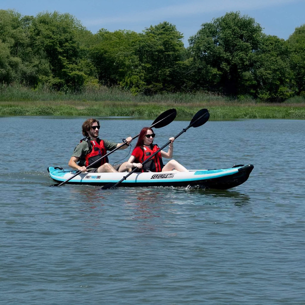 Two People Kayaking On A Calm Lake With Trees In The Background - Saksby Wholesale