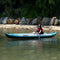 Person Paddling A Sea Eagle Kayak On A Calm Body Of Water With A Rocky Shoreline And Greenery In The Background. - Saksby Wholesale